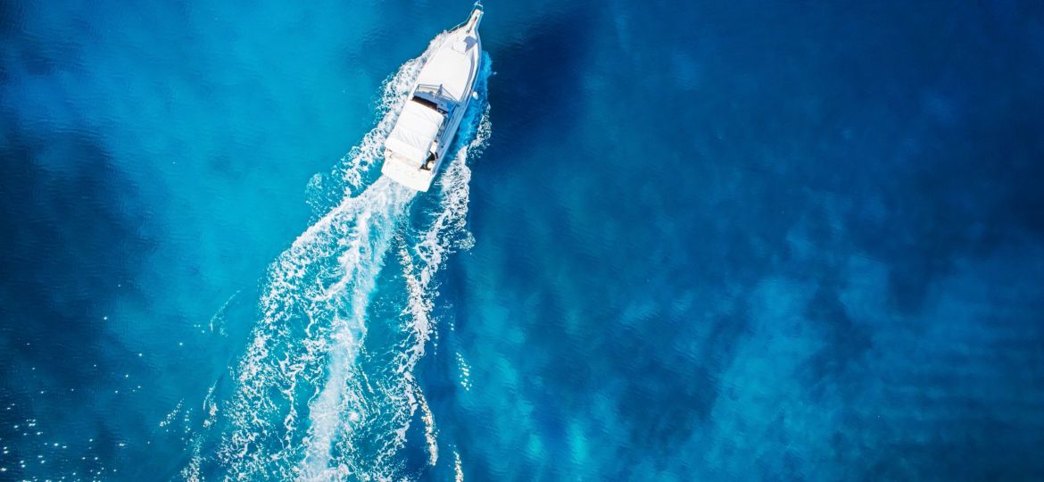 white boat making waves through blue water