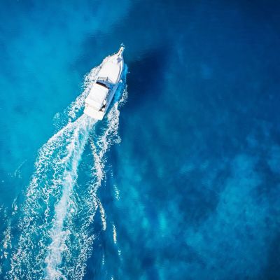 white boat making waves through blue water